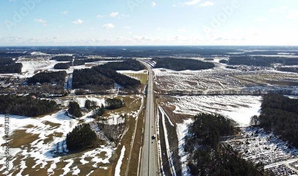 Fototapeta Top view of asphalt highway road among snow fields in winter