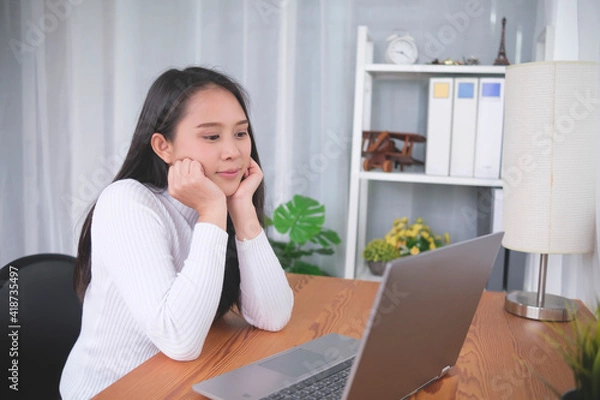 Fototapeta Happy smiling young Asian woman enthusiastic watching video call conference online internet movie entertainment living at home relaxing life style, student online class learning education quarantine