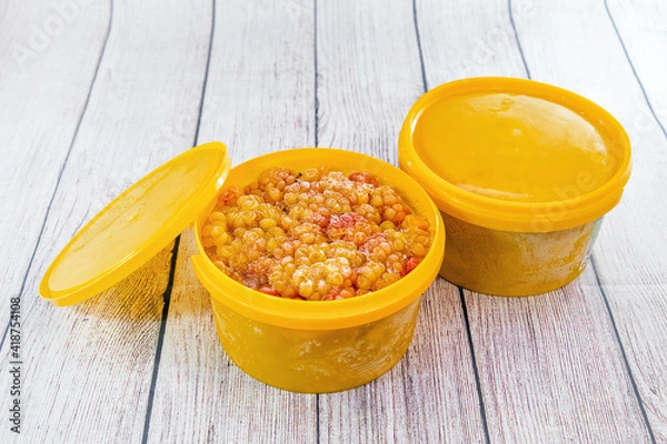 Obraz Frozen cloudberries in yellow plastic containers