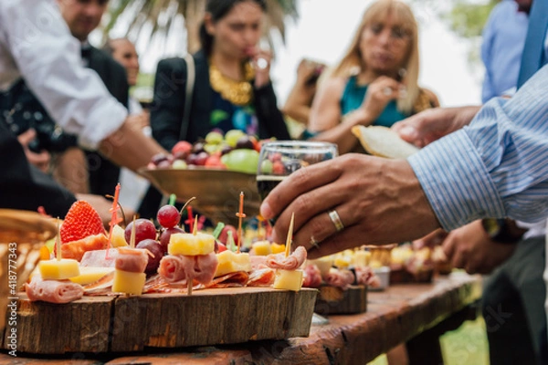 Obraz Manos tomando alimentos de una mesa de banquete