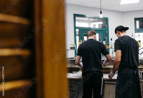 Fototapeta Two chefs in the process of working in a pizzeria restaurant