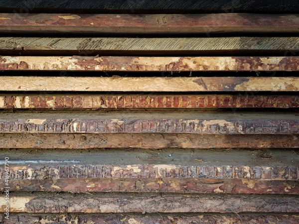 Fototapeta natural wooden boards stacked in a row on top of each other in a horizontal position as a background. decorative solution, shabby brown wooden planks with shabby bark. in the daytime, without people. 