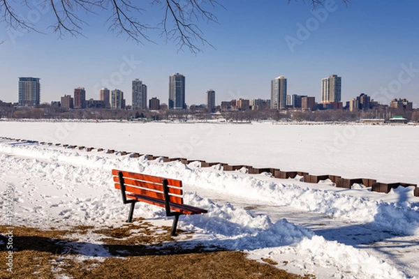 Obraz A bench along the shore of the Milwaukee, Wisconsin Harbor waits for springtime visitors
