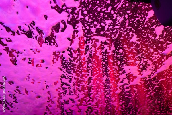 Obraz Soap and lights create abstract patterns on a windshield in the car wash.
