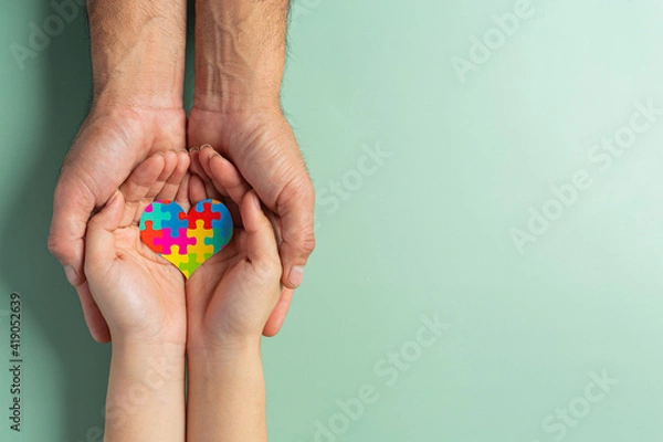 Obraz Adult and child hands holding jigsaw puzzle heart shape, World Autism Awareness Day