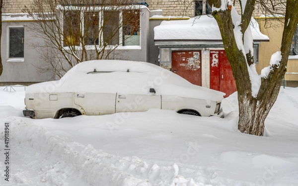 Fototapeta City street after blizzard. Stuck cars under the snow and ice. Buried vehicle in snowdrift on the road. Parking lots in winter after heavy snowfall. Uncleaned roads. Record-breaking amounts of snow.