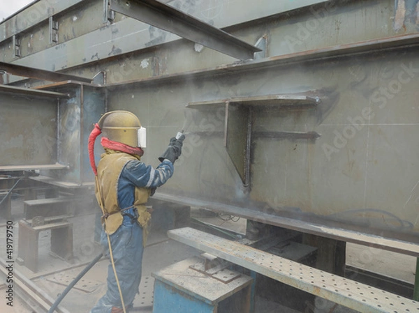 Fototapeta Worker is sandblasting a welding surface and steel structure with pressure blasting pot for create surface profile of steel before painting.