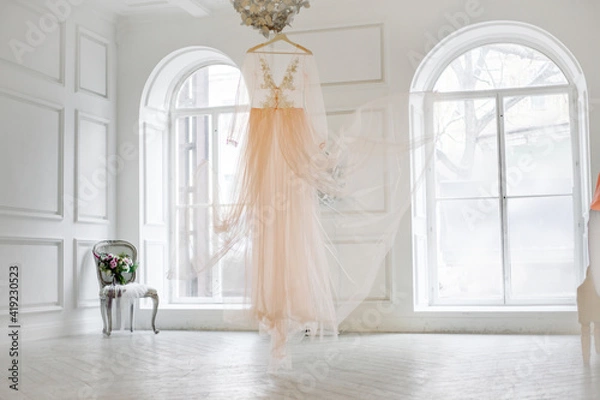 Obraz Classic white interior with large windows. Wedding dress in the center of the room