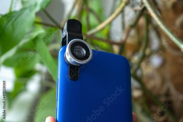 Fototapeta Overhead phone lens with clips on the blue modern smartphone. Extra macro camera for mobile device