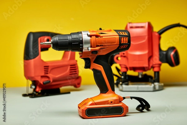 Fototapeta screwdriver, red battery drill with jigsaw in the background, copy space tools instruments