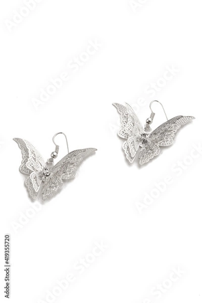 Fototapeta Subject shot of two hook silver earrings decorated with pendants made as fancy butterflies with lace wings. The pair of fantasy earrings is isolated on white background.