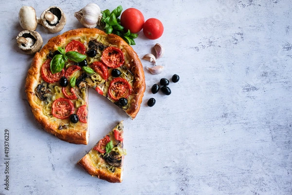 Fototapeta  Vegetarian homemade pizza on a light background with a cut piece. Next ingredients -mushrooms, tomatoes, garlic, Basil, olives.   The concept of healthy eating.