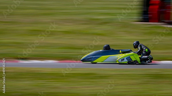 Fototapeta A panning shot of a racing sidecar as it corners on a track.
