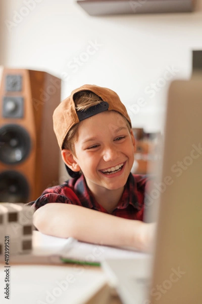 Fototapeta Happy little boy using a computer at home.