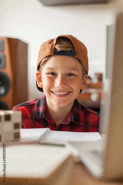 Fototapeta Happy elementary student with a cap at home.