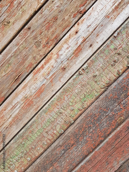 Fototapeta textured background of old time-worn wooden planks, set at an angle of 45 degrees, from a mixture of red, white and brown colors, siding of a wood panel of an old house, close-up, no people, patern. 
