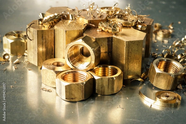 Fototapeta Hexagonal bars and brass products made on CNC metalworking machines. Manufacturing of parts from brass. Close-up. 