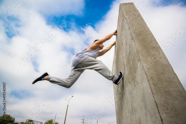 Fototapeta Man engaged in parkour jumping on the street 