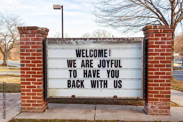 Fototapeta A large notice board in front of a public school in Maryland has a message to students who have been away due to COVID-19 pandemic. It reads welcome, we are joyful to have you back with us.