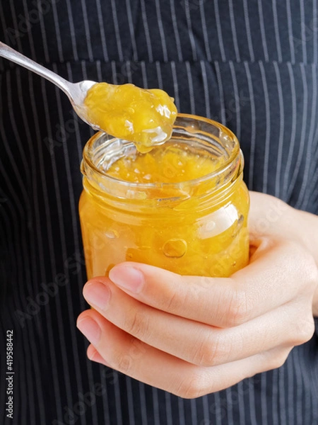 Fototapeta Red and yellow jam on plank wood and slice bread.