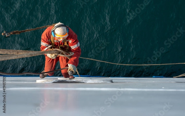 Obraz Seaman ship crew working aloft at height derusting and getting vessel ready for painting.
