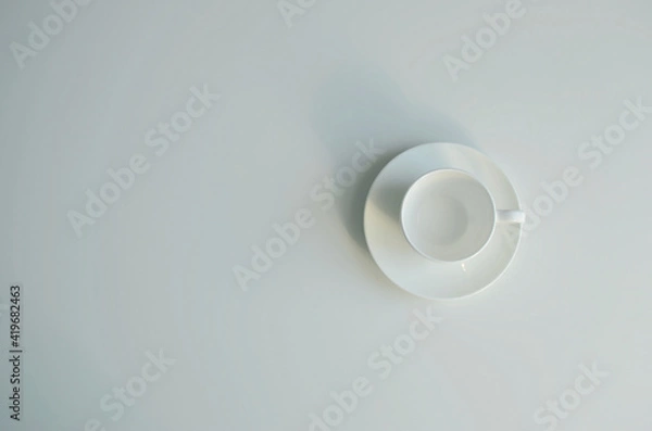 Fototapeta White ceramic empty cup on saucer top view, copy space