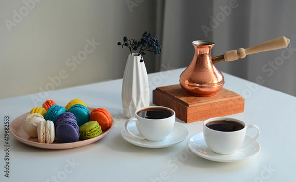 Fototapeta Two cup of coffee, multicolored macaroons, turkish coffee pot on white background, top view