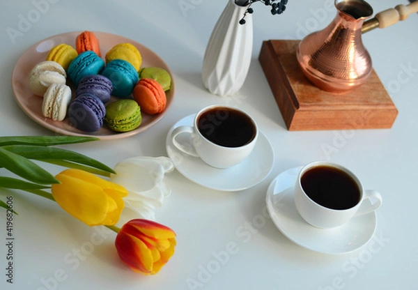 Fototapeta Two cup of coffee, multicolored macaroons, turkish coffee pot on white background, top view