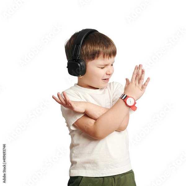Obraz isolated child in headphones listens to music and sings on white background. happy little boy. cross arms.