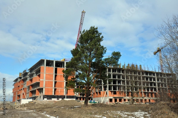Fototapeta The process of building a multi-storey residential building made of red brick.