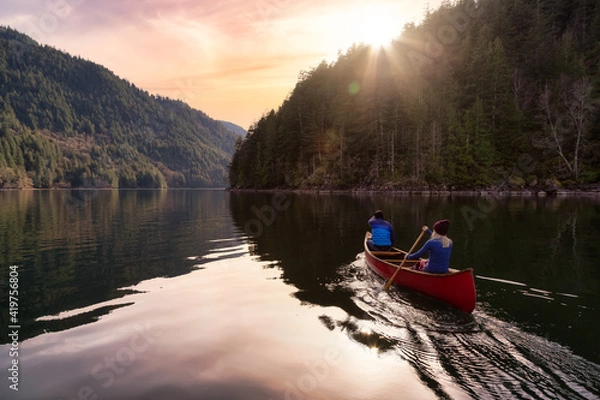Fototapeta Couple friends canoeing on a wooden canoe during a colorful sunny sunset. Cloudy Sky Artistic Render. Taken in Harrison River, East of Vancouver, British Columbia, Canada.