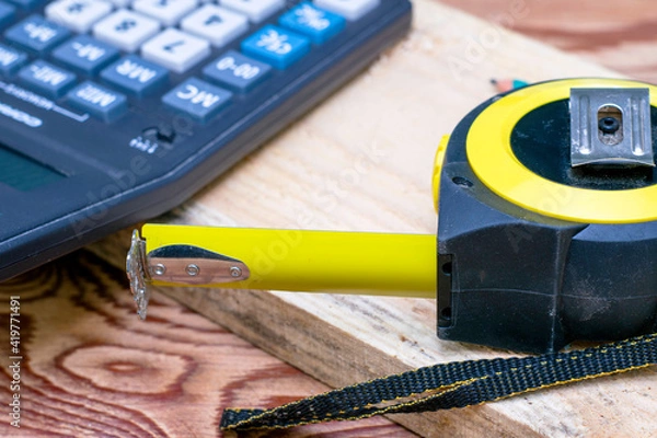 Obraz construction meter-tape measure calculator for calculations pencil and wooden board are on the workbench