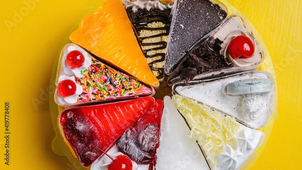 Fototapeta Multiple flavored slices cake for birthday on yellow background.