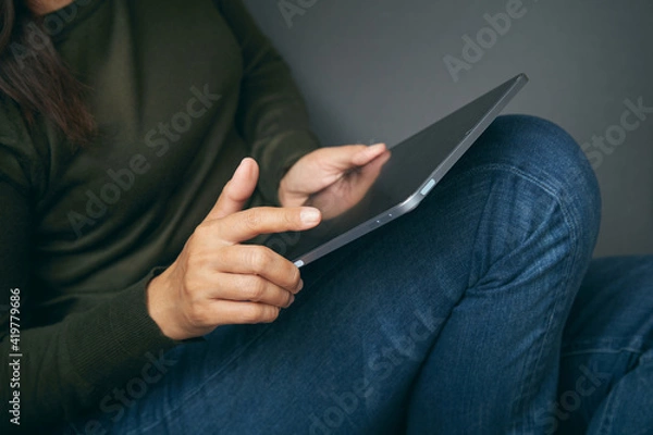 Fototapeta Zbliżenie kobiety siedzącej w kącie trzymającej cyfrowy tablet. Ręczne wskazanie i dotykanie ekranu tabletu palcem.