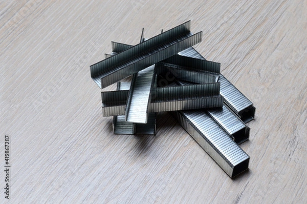 Fototapeta a bunch of staples for an industrial stapler lie on the tabletop.