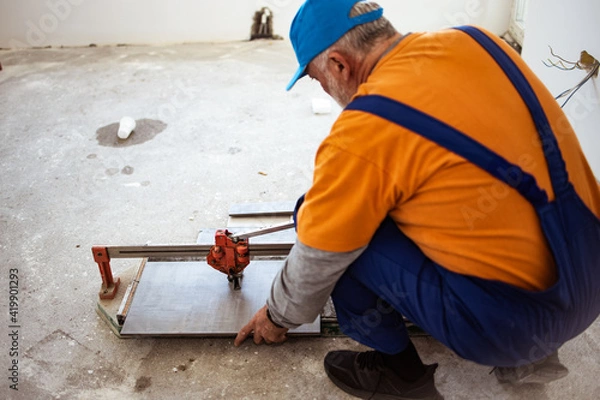 Obraz Handyman cutting ceremic tiles on the flor