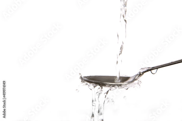 Obraz Clear water splashing onto metal spoon.