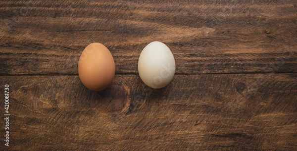 Obraz two different colored chicken eggs on wooden background