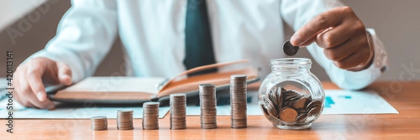 Fototapeta Financial businessman with coins put in a jar, Saving money for future growth and knowing how to manage your spending wisely, Saving money for business growth or long-term profitability.