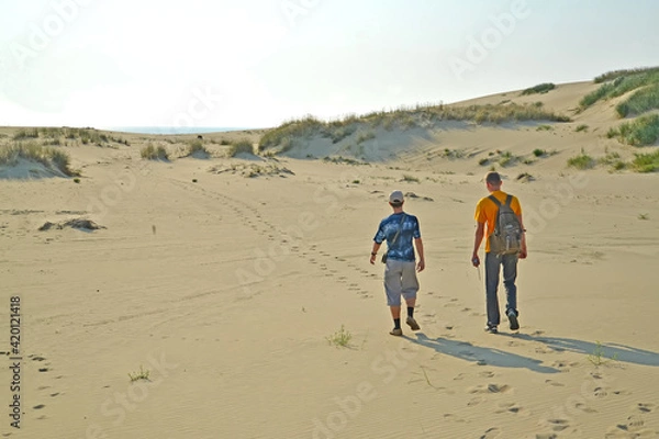 Fototapeta Two young tourists in the sand dunes of the Curonian Spit. Kaliningrad region
