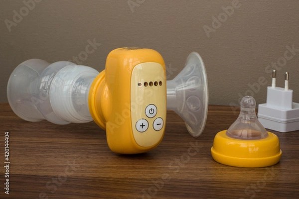 Obraz breast pump yellow on a wooden table