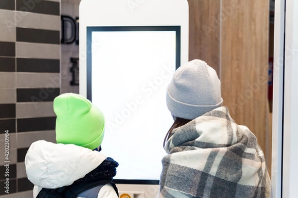 Obraz Self service restaurant, kiosk, terminal. Two girls near an empty screen order food