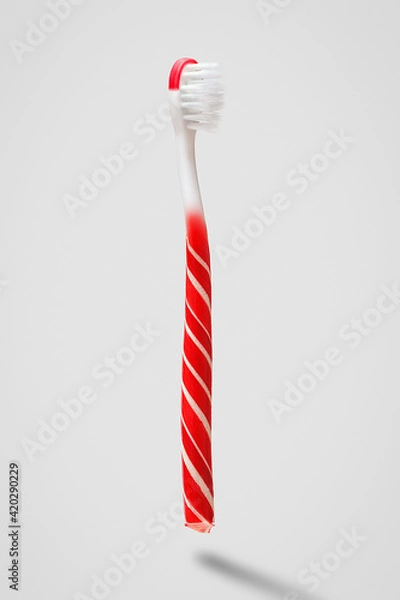 Fototapeta Creative concept of oral hygiene. Toothbrush in the shape of a lollipop on a gray background.
