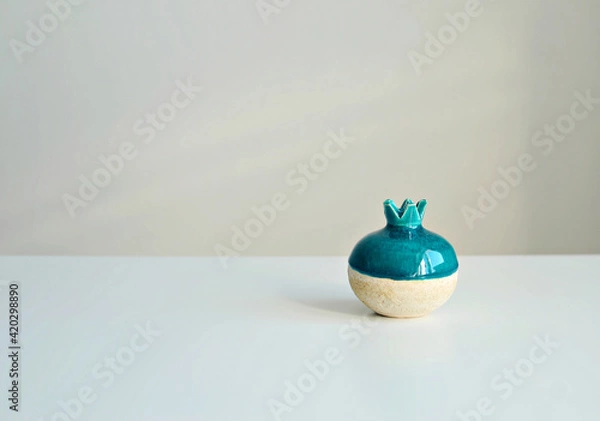 Fototapeta Turquoise vase in the form of a pomegranate on a white background, close-up. Stylish interior mockup, copy space.