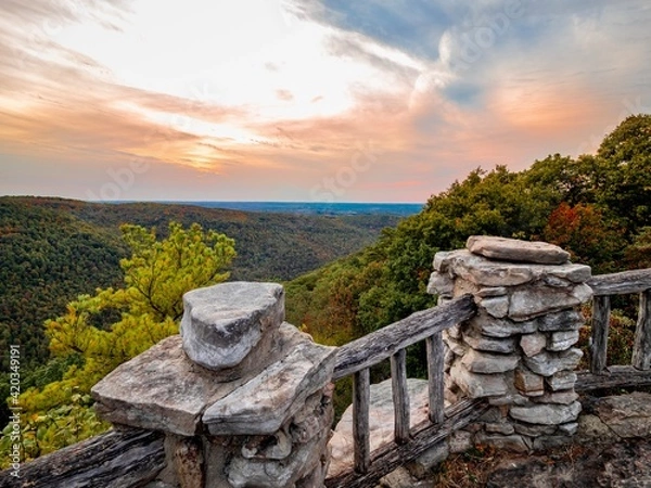 Obraz Overlook of the mountains and the fall foliage at Coopers Rock State Forest in West Virginia with the sunset golden sky one direction and a blue swirly sky the other direction, with the rock cliff.