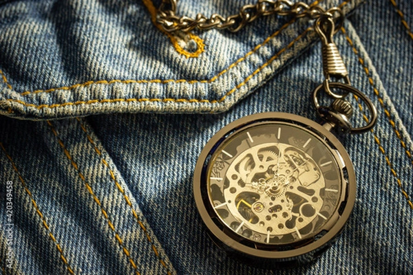 Fototapeta Vintage pocket watch is placed over an old blue denim shirt and the morning sun shines down in the top right corner. The concept of time importance. Closeup and copy space for text or your article.