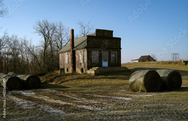 Fototapeta A boarded up country store in Pure Air, Missouri surrounded by hay bales with a barn in the background. 2007