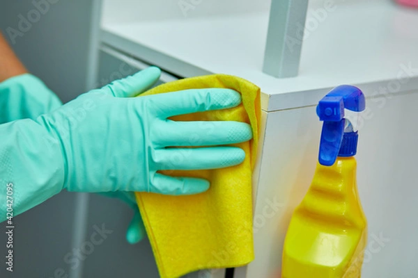 Fototapeta Bearded man cleaning home table surface with towel and gloves, disinfectant spray bottle