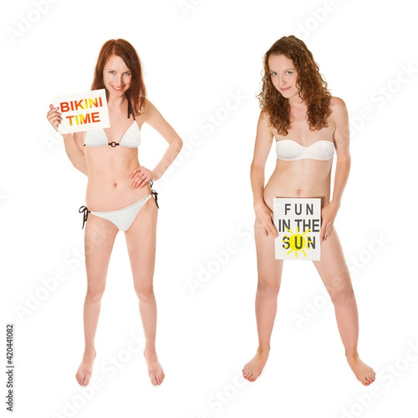 Fototapeta Full length portraits of two beautiful young women wearing white bikinis and holding papers in their hands, bikini time and fun in the sun is written on the papers, isolated on white studio background