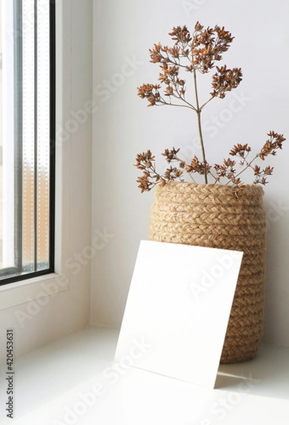 Obraz Empty mockup poster. Blank square greeting  card on window. Dried flowers in a knitted jute vase. Minimal interior design. Modern style.